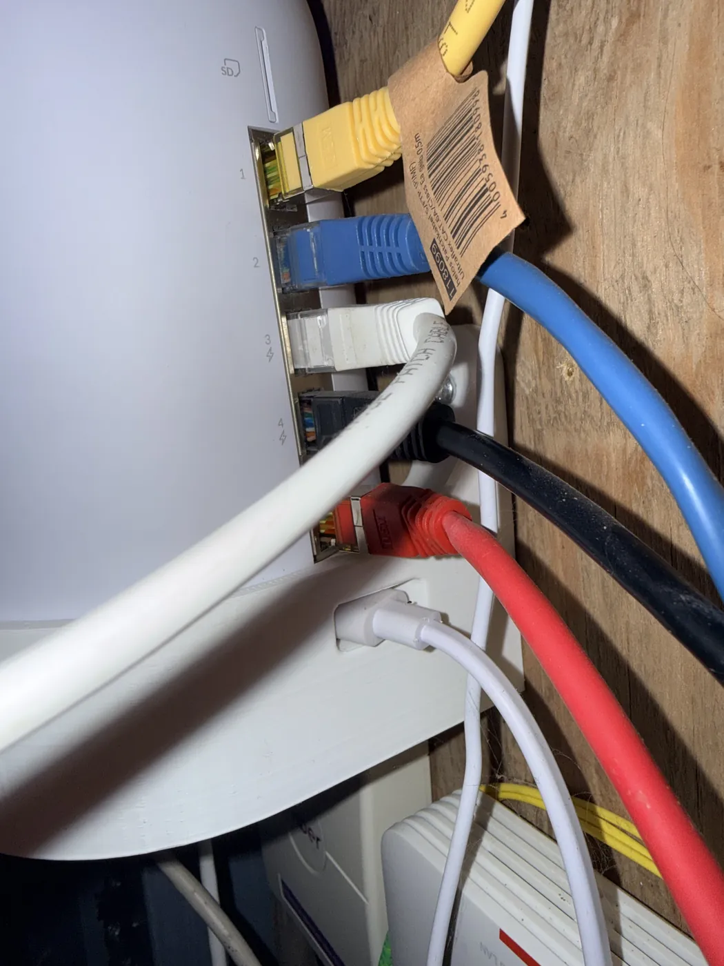 De UniFi-router in de meterkast met gele, blauwe, witte, zwarte en rode netwerkkabels
