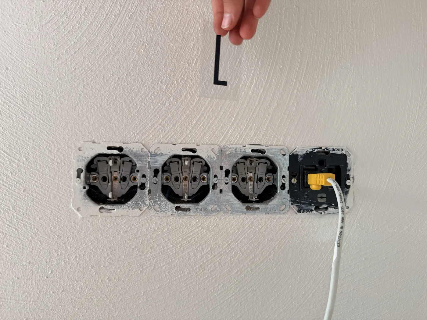 Opengewerkte groep van drie stopcontacten en een netwerkaansluiting, met stickerletter L