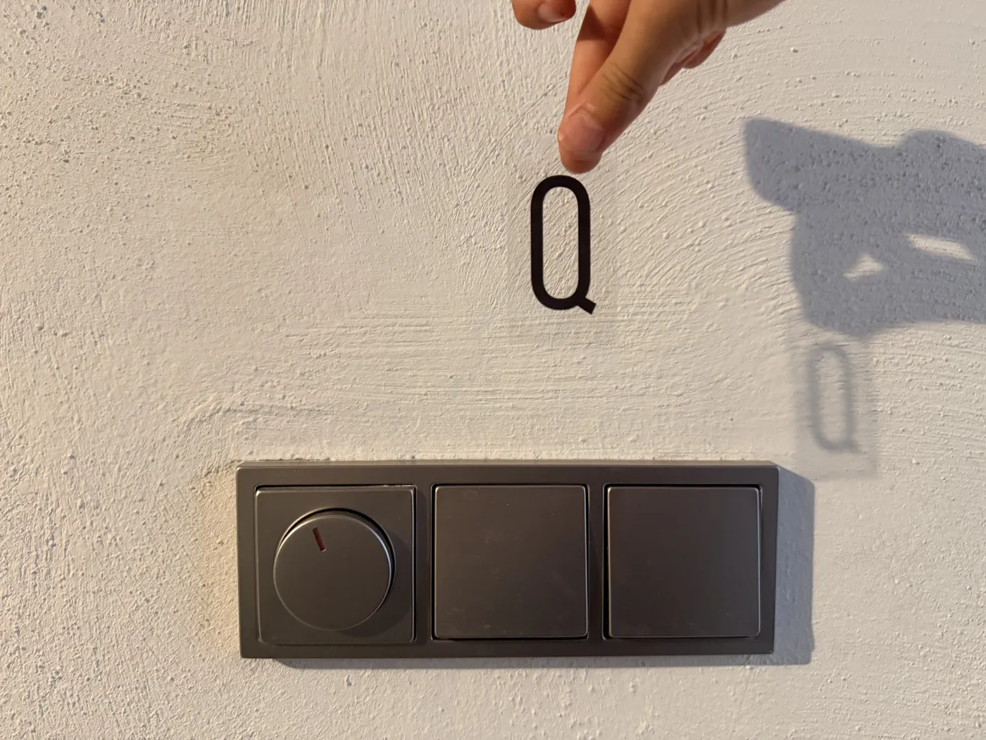 Oude grijze schakelaarcombinatie met dimmer, met stickerletter Q erboven